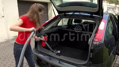 女人用吸尘器清洁车内行李箱。